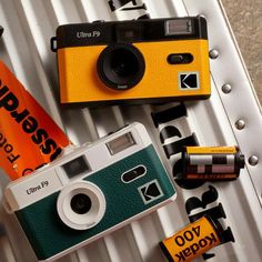 an orange and green camera sitting on top of a metal shelf next to batteries,