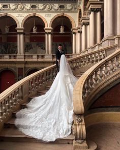 a bride and groom are standing on the stairs in an ornately decorated building with stone balconies