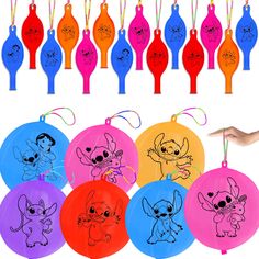 a bunch of different colored frisbees with cartoon characters drawn on them and hanging from strings