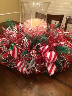 a christmas wreath sitting on top of a wooden table next to a glass vase filled with candy