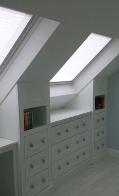 an attic bedroom with white furniture and skylights