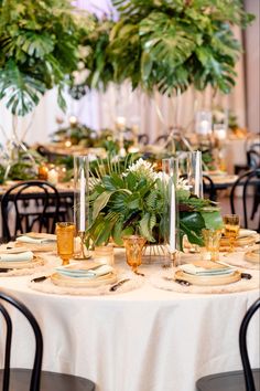 the table is set with place settings and greenery