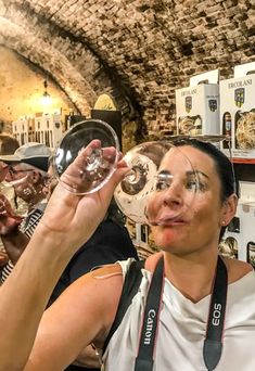 a woman holding a wine glass up to her face in front of a group of people