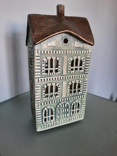 a white ceramic house with brown roof sitting on top of a table