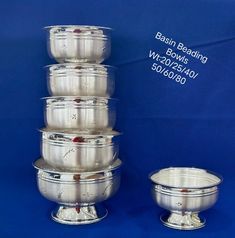 a stack of silver bowls sitting next to each other on top of a blue background