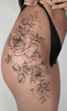 a woman's thigh with flowers on it and her cell phone in her hand