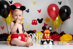 a baby sitting in front of mickey mouse cake