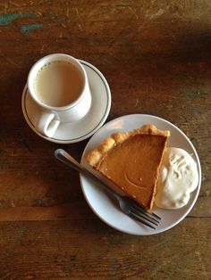 a piece of pie on a plate next to a cup of coffee