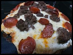 a pepperoni and sausage pizza sitting on top of a black tablecloth covered surface