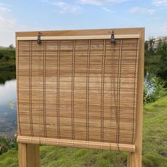 a wooden sign sitting on the side of a lush green field next to a lake