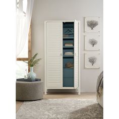 a tall white cabinet with blue drawers in a room next to a rug and window