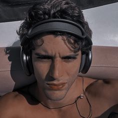 a shirtless man wearing headphones on top of a boat in the sun with his eyes closed