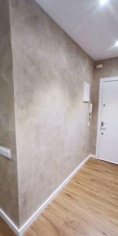 an empty room with hard wood floors and white door in the corner on the wall