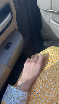 a person's hand resting on the seat of a car, next to an arm rest