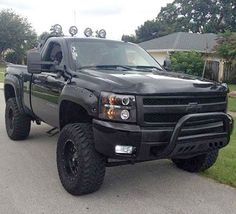 a large black truck parked on the side of a road in front of a house