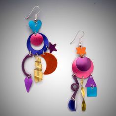 two pairs of colorful earrings hanging from hooks on a gray background with white space for text