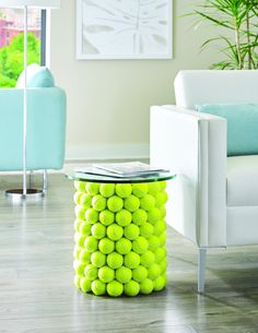 a table made out of tennis balls in a room with white furniture and green plants