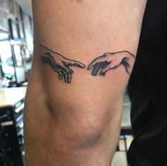 the creation of man's hands tattoo on the right leg is shown in black ink