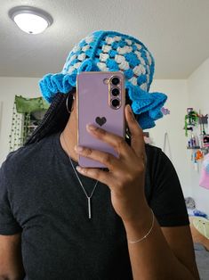 a woman taking a selfie with her cell phone wearing a knitted hat on top of her head