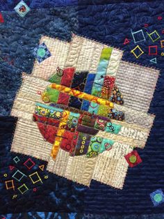 a close up of a quilt with many different designs and colors on it, as well as the center piece