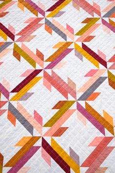 a colorful quilt with many different colored strips on the top and bottom, as well as an arrow pattern