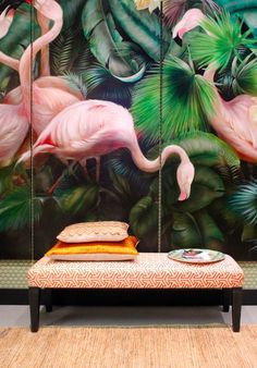 two pink flamingos hanging from the side of a wall next to pillows on a bed