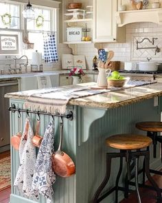 a kitchen with white cabinets and an island in the middle, filled with pots and pans