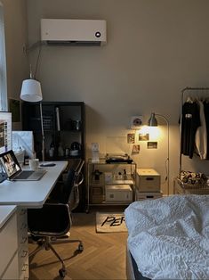 a bedroom with a bed, desk and computer on the table in front of it