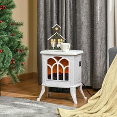 a small white table with a christmas tree in the corner