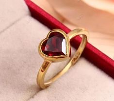 a gold ring with a heart shaped red stone