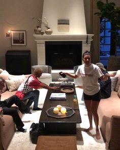 a woman standing in front of a coffee table with fruit on it and people sitting around