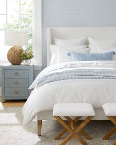 a white bed sitting in a bedroom next to a window with lots of light on it