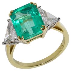 Introducing our exquisite 18kt Yellow Gold and Platinum Three-Stone Emerald and Diamond Ring, crafted circa the late 1990s. This hallmark piece features a timeless design, marked with an 18kt gold stamp. The ring boasts clean lines and a modern aesthetic, highlighted by a stunning central emerald totalling 3.00 carats and a two trillion-cut diamonds, tolling 1.60 carats. The emerald, cut in a classic emerald style, showcases the gemstone's clarity and vibrant colour through its large, open facets. Set in a luxurious yellow gold setting, the emerald is perfectly complemented by the brilliance of the trillion-cut diamonds, which are set in platinum prongs. This combination enhances their sparkle and adds a touch of sophistication. Dimensions - Ring Size (UK) = M 1/2 (EU) = 54.5 (US) = 6.75 W Columbian Emeralds, Emerald Style, Emerald Cut Diamond Ring, Emerald And Diamond Ring, Emerald Diamond Ring, Three Stone Diamond, Yellow Gold Setting, Emerald Stone, Emerald Cut Diamonds