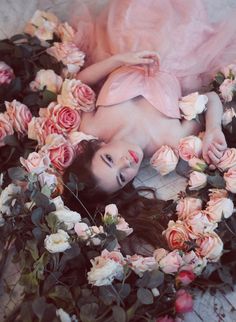 a woman laying on the ground surrounded by flowers