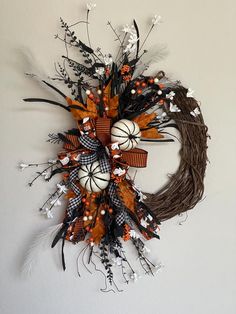 a wreath is hanging on the wall with pumpkins and other decorations around it,