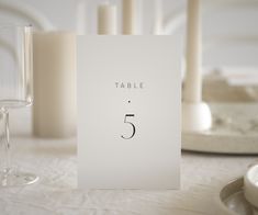 a table number is placed on top of a card next to some wine glasses and candles