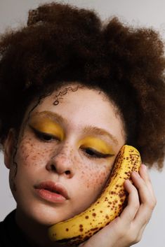 a woman with freckles on her face holding a banana