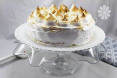 a cake with white frosting and gold decorations on top is sitting on a glass stand