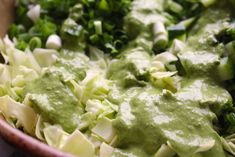 a wooden bowl filled with green vegetables and dressing on top of it's side