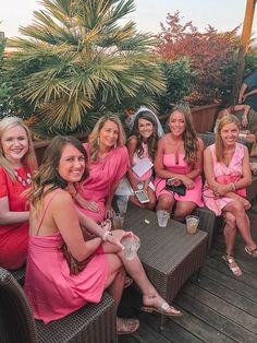 a group of women in pink dresses sitting around each other