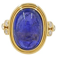 This exquisite ring features a stunning 10.85-carat Tanzanite, set in luxurious 18 Karat Yellow Gold. The deep blue-violet hue of the Tanzanite is beautifully complemented by the warm tone of the yellow gold, creating a striking and elegant contrast. The oval-cut Tanzanite is the centerpiece of the ring, its rich color and size making it a truly captivating piece. Flanking the Tanzanite are three sparkling diamonds on each side, totaling 0.20 carats, adding a touch of brilliance and sophistication. These diamonds are meticulously set, enhancing the overall sparkle and elegance of the design. This ring is a timeless piece that combines classic elegance with the unique beauty of Tanzanite, making it a perfect choice for those who appreciate fine jewelry with a distinctive character. 18K Yell Luxury Yellow Oval Cabochon Rings, Luxury Contemporary Oval Jewelry, Tanzanite Stone, Tanzanite Diamond, Pink Sapphire Ring, Bleu Violet, Warm Tone, Diamond Cocktail Rings, Yellow Gold Setting