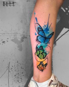 a colorful butterfly tattoo on the left arm and leg, with watercolor splashs