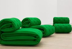 three green couches sitting on top of a hard wood floor next to each other