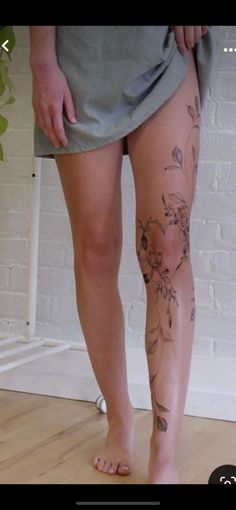 a person with tattoos on their legs standing in front of a brick wall and floor