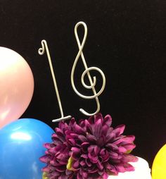 there is a cake with a music note on it and balloons in the back ground