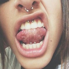 a woman with piercings on her nose and tongue