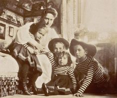 an old black and white photo of four women sitting on a couch with their children