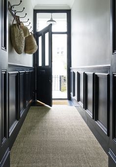 a hallway with black doors and two baskets hanging on the wall above an area rug