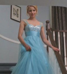 a woman in a blue dress standing on the stairs