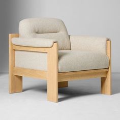 a white chair sitting on top of a gray floor next to a wooden armrest